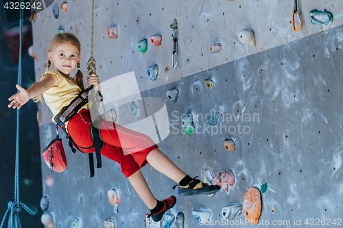 Image of little girl climbing a rock wall indoor