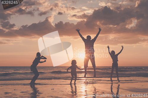 Image of Father and children playing on the beach at the sunset time.