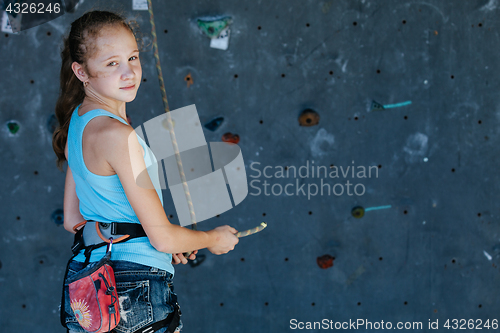 Image of One teenager climbing a rock wall indoor.