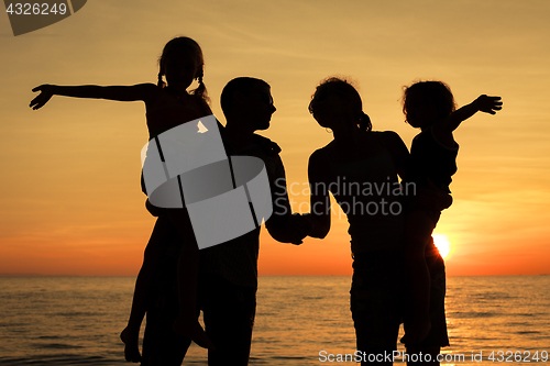 Image of Silhouette of happy family who playing on the beach at the sunse