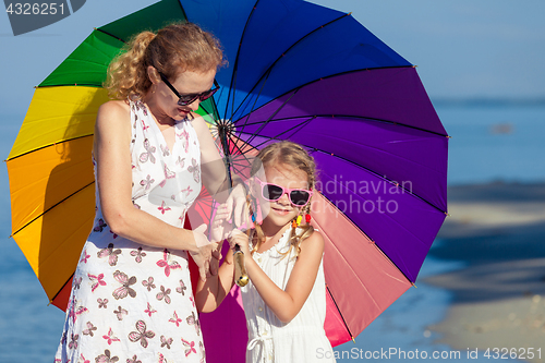 Image of Mother and daughter playing with umbrella on the beach at the da