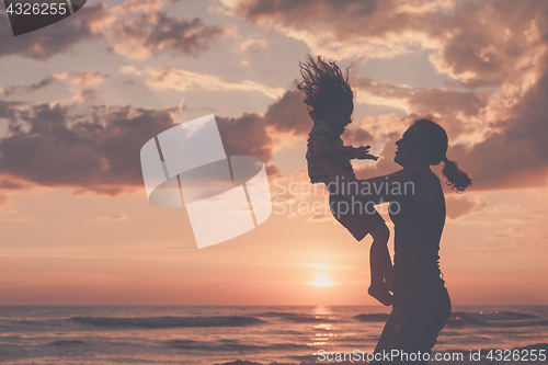 Image of Mother and son playing on the beach at the sunset time.