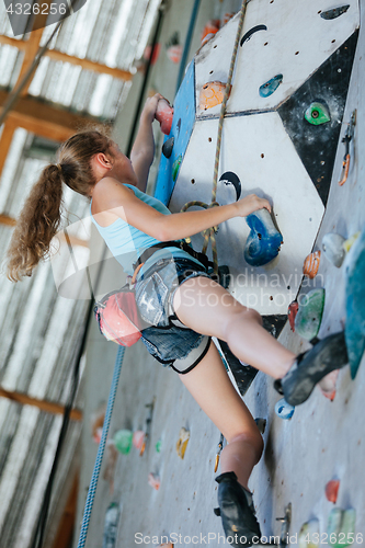 Image of One teenager climbing a rock wall indoor.