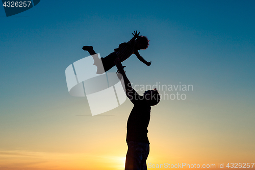 Image of Father and son playing in the park at the sunset time.