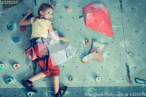 Image of little girl climbing a rock wall indoor