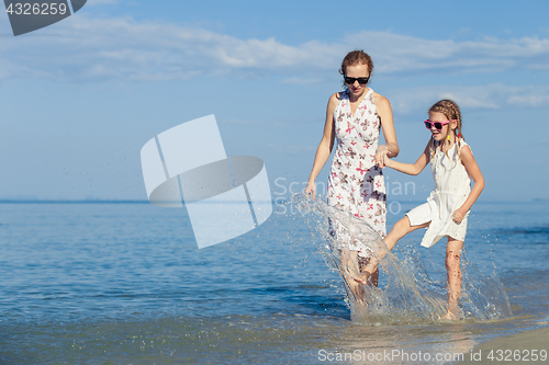 Image of Mother and daughter playing  on the beach at the day time.