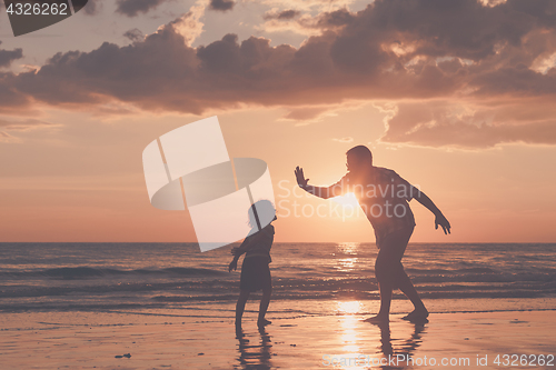 Image of Father and son playing on the beach at the sunset time.