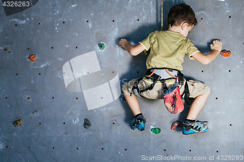 Image of little boy climbing a rock wall indoor