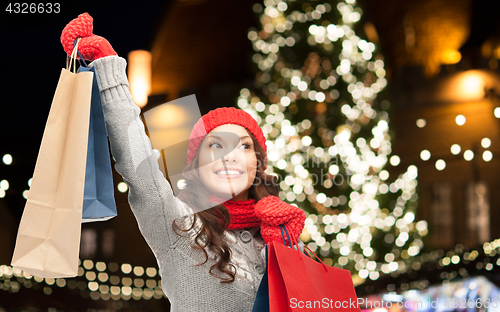 Image of happy woman with shopping bags over christmas tree