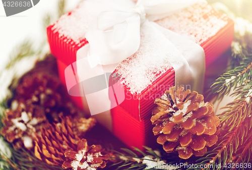 Image of close up of christmas gift and fir wreath on snow