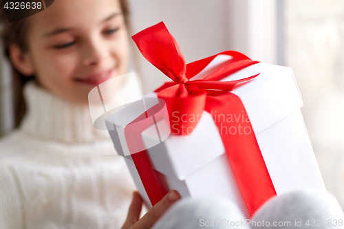 Image of girl with christmas gift sitting on sill at home