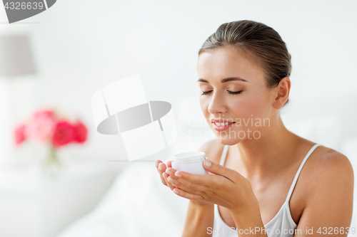 Image of close up of happy woman holding and smelling cream