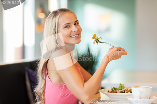 Image of happy young woman eating lunch at restaurant