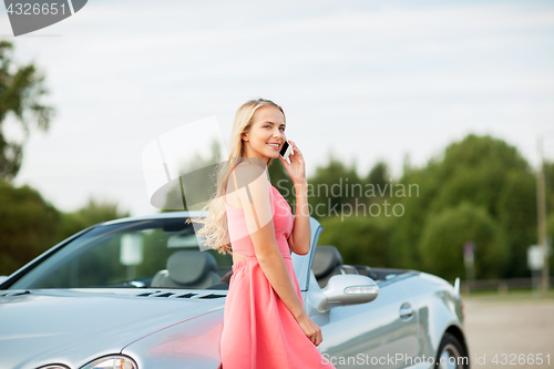 Image of woman calling on smartphone at convertible car