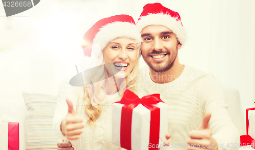 Image of happy couple with christmas gifts and thumbs up