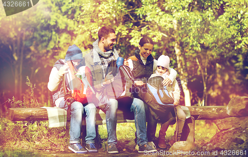 Image of happy family with backpacks and thermos at camp