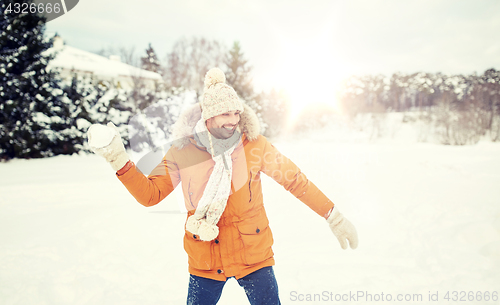 Image of happy young man playing snowballs in winter