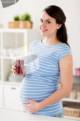 Image of happy pregnant woman drinking juice at home