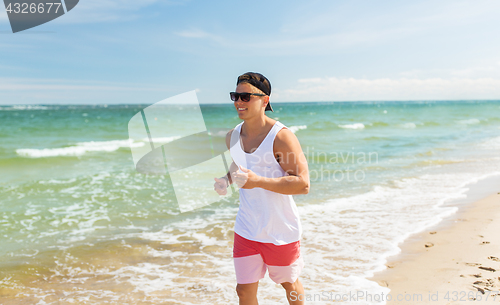 Image of happy man running along summer beach