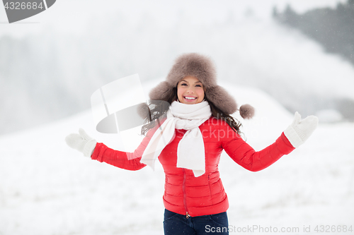 Image of happy smiling woman in winter fur hat outdoors