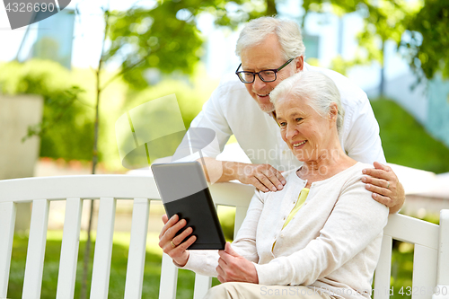 Image of happy senior couple with tablet pc at summer park