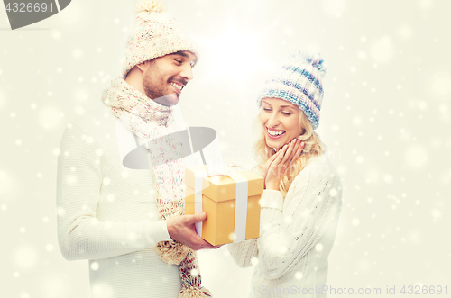 Image of smiling couple in winter clothes with gift box