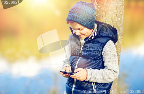 Image of happy boy playing game on smartphone outdoors