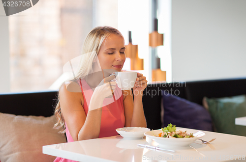 Image of woman eating and drinking coffee at restaurant