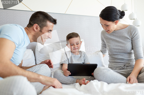 Image of happy family with tablet pc in bed at home