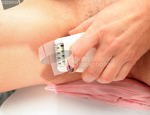 Image of woman is shaves by epilator