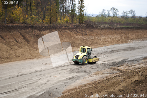 Image of asphalt paver rolls out crushed stone