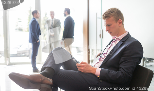 Image of Businessman using smart phone while sitting in waiting room.