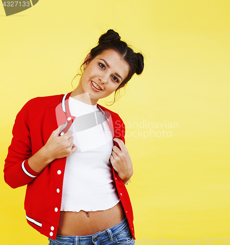 Image of young pretty teenage woman happy smiling posing on yellow background, fashion lifestyle people concept 