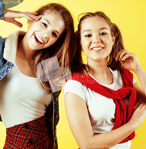 Image of lifestyle people concept: two pretty young school teenage girls having fun happy smiling on yellow background 