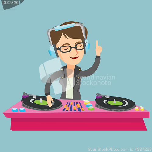 Image of Young caucasian DJ mixing music on turntables.