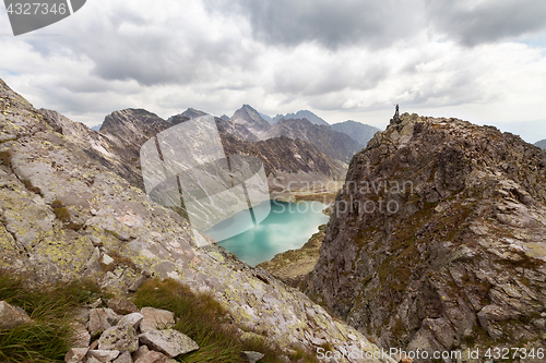 Image of Hiking woman standing on high peak and pointing on rocky Tatra mountains