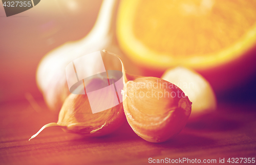 Image of close up of garlic and orange on wooden table