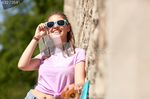 Image of happy teenage girl in shades with longboard