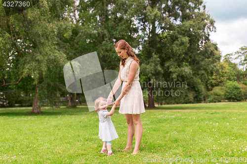 Image of happy mother playing with baby girl at summer park