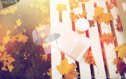 Image of newspaper and coffee cup on bench in autumn park
