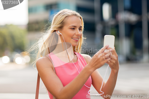 Image of happy young woman with smartphone and earphones