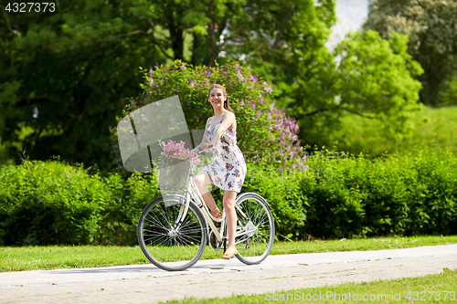 Image of happy woman riding fixie bicycle in summer park