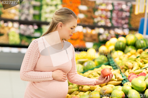 Image of happy pregnant woman with pomegranate at grocery