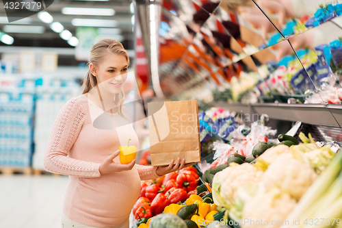 Image of pregnant woman buying vegetables at grocery store