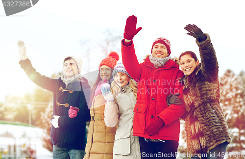 Image of happy friends waving hands outdoors