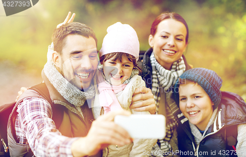 Image of family taking selfie with smartphone in woods