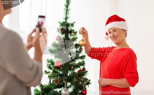 Image of happy senior woman decorating christmas tree