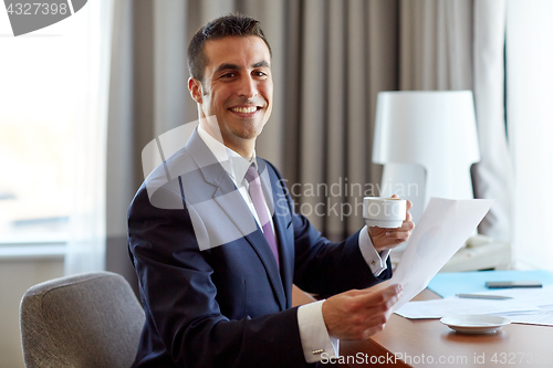 Image of businessman with papers drinking coffee at hotel
