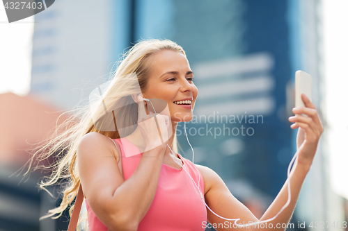 Image of happy young woman with smartphone and earphones