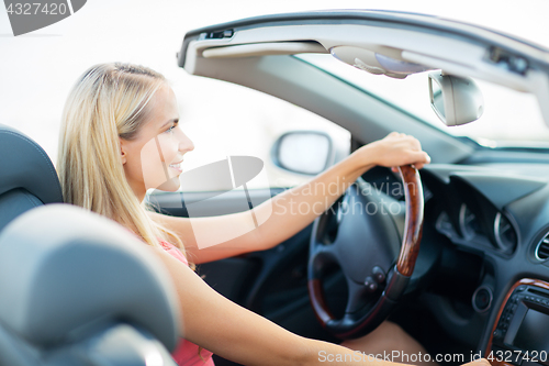 Image of happy young woman driving convertible car